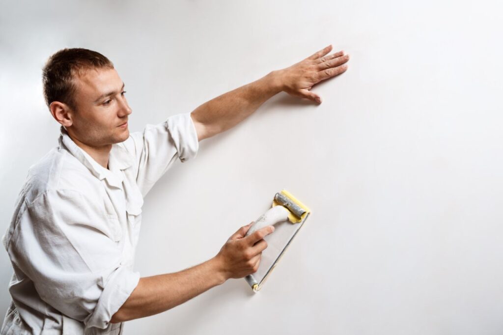 worker grinding white wall with sandpaper (1)